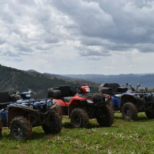 a group of four atvs parked on top of a lush green hillside